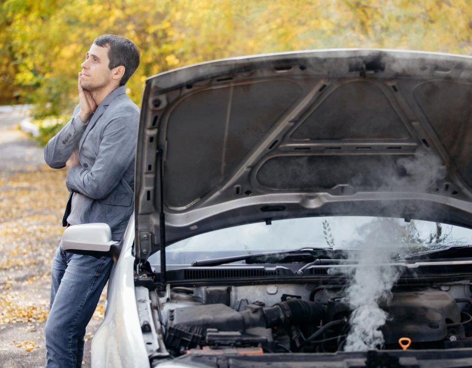Persoană îngrijorată neștiind de ce iese fum de la motorul mașinii.